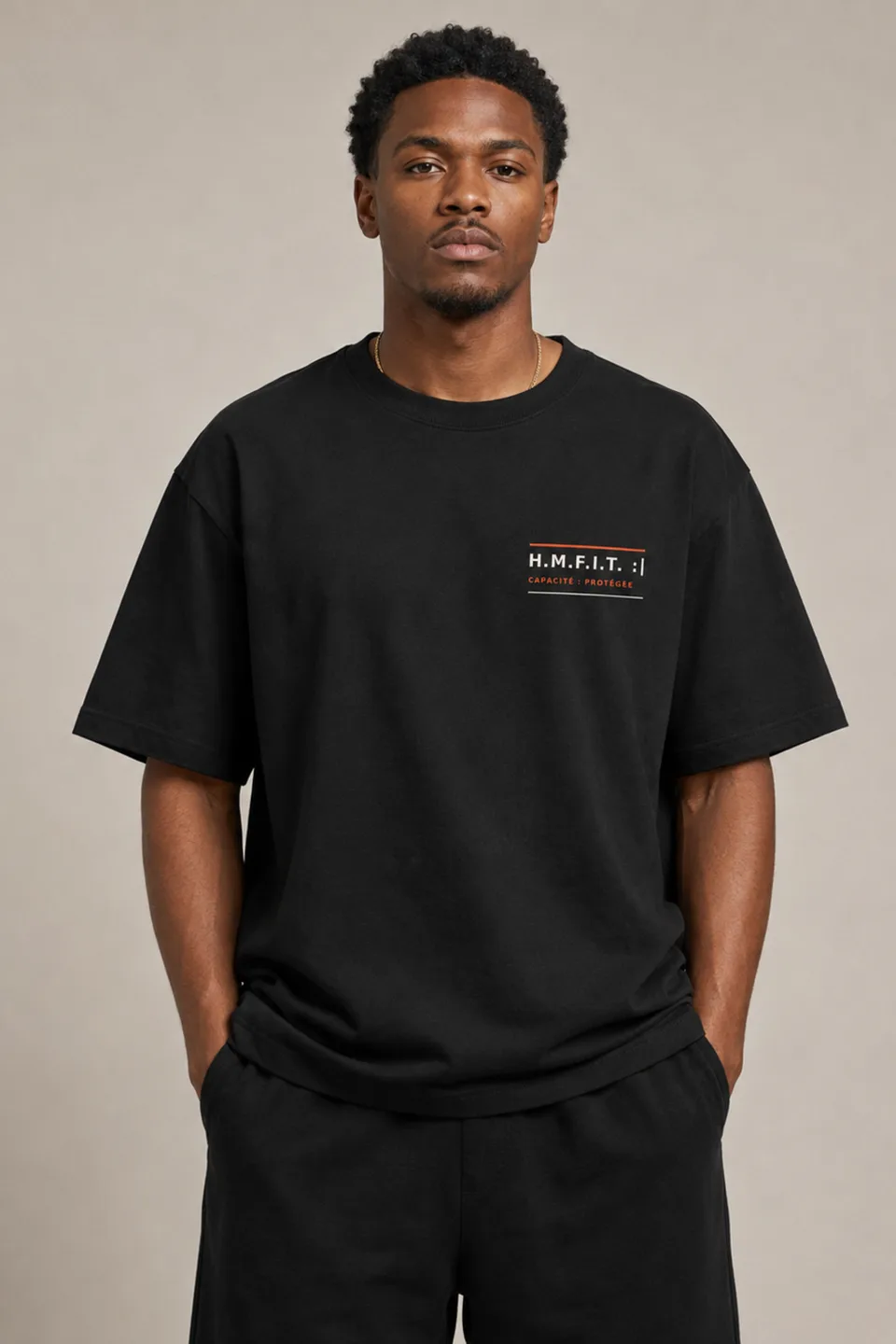 Le même t-shirt GEN/01, porté par quelqu’un d’autre — même inscription : « H.M.F.I.T. :| — CAPACITÉ : PROTÉGÉE ».